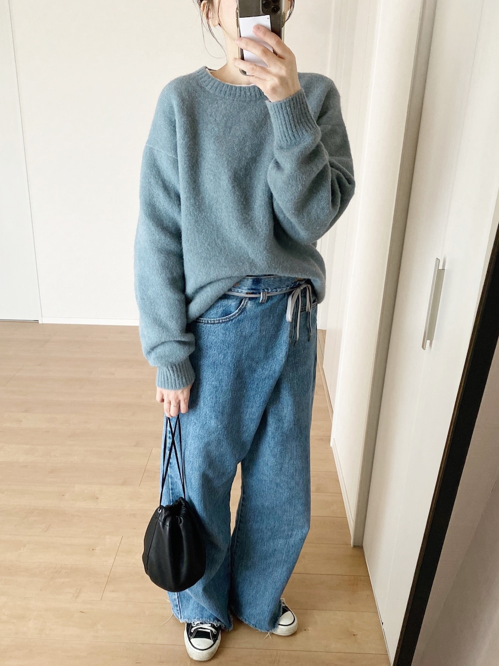 ブルー系のニット/セーター、ブルー系のデニムパンツ、ブラック系のハンドバッグを着用したレディースの冬コーディネートの1枚目の写真