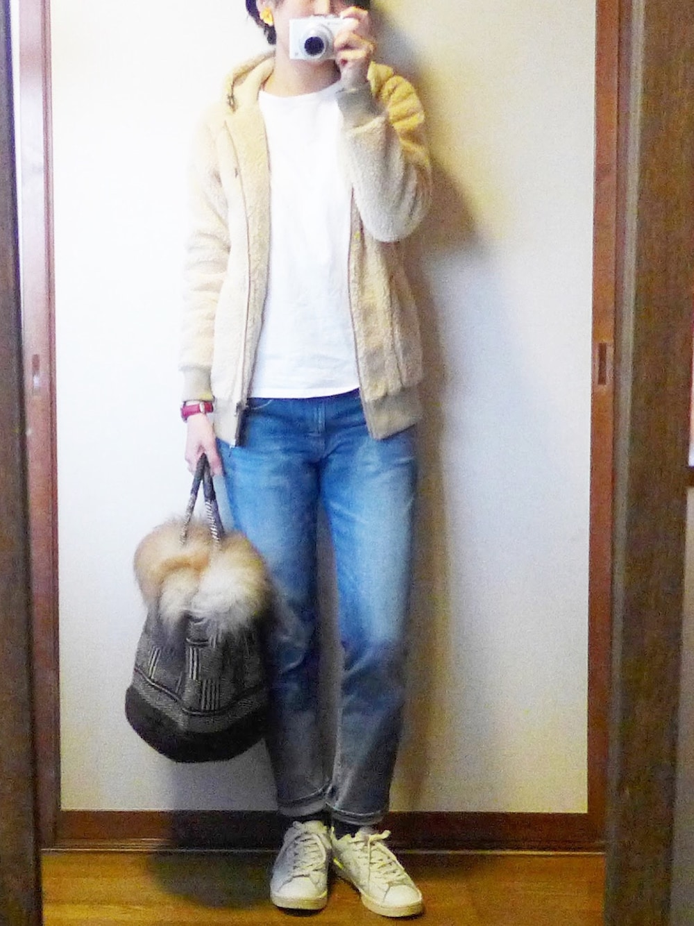 パーカー、ブルー系のデニムパンツ、ブラウン系のバッグを着用したレディースの冬コーディネートの1枚目の写真