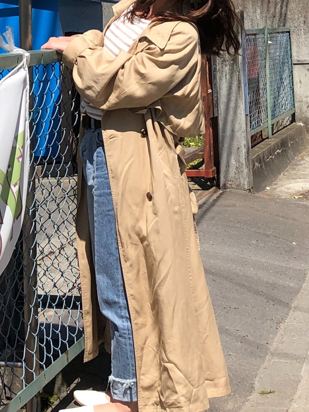 ベージュ系のトレンチコート、ブルー系のデニムパンツ、ベージュ系のTシャツ/カットソーを着用したレディースの秋コーディネートの1枚目の写真