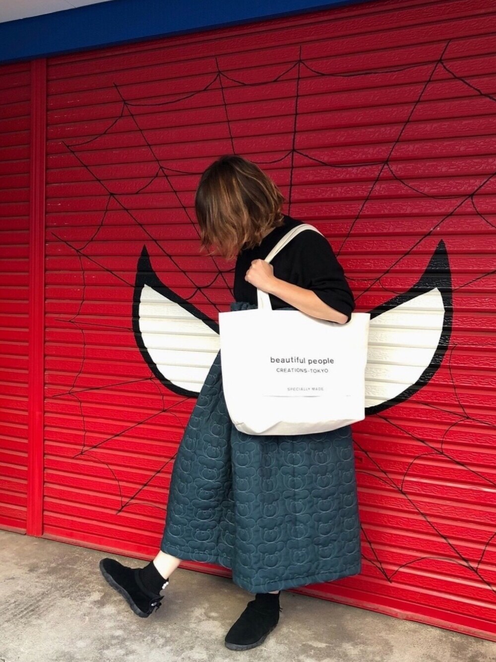 グリーン系のスカート、ブラック系のスニーカー、ホワイト系のトートバッグを着用したレディースの秋コーディネートの1枚目の写真