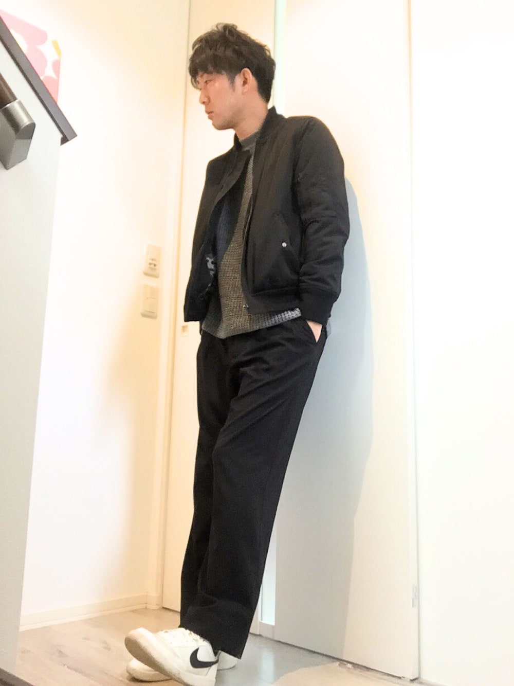 ブラック系のミリタリージャケット、グレー系のニット/セーター、ブラック系のスラックスを着用したメンズの冬コーディネートの1枚目の写真