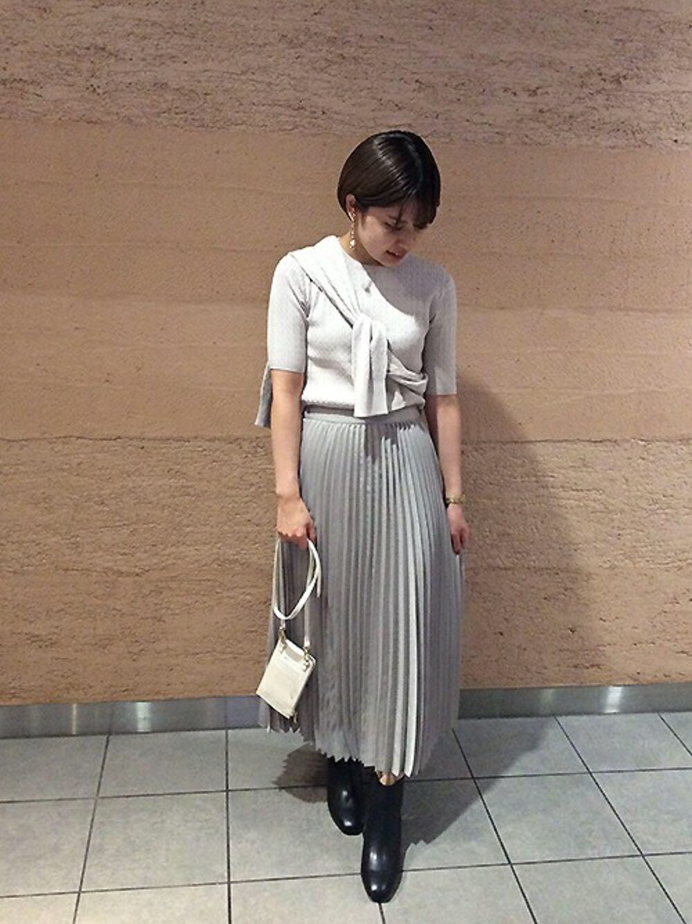 グレー系のその他トップス、ブラック系のブーツ、ホワイト系の財布を着用したレディースの秋コーディネートの1枚目の写真