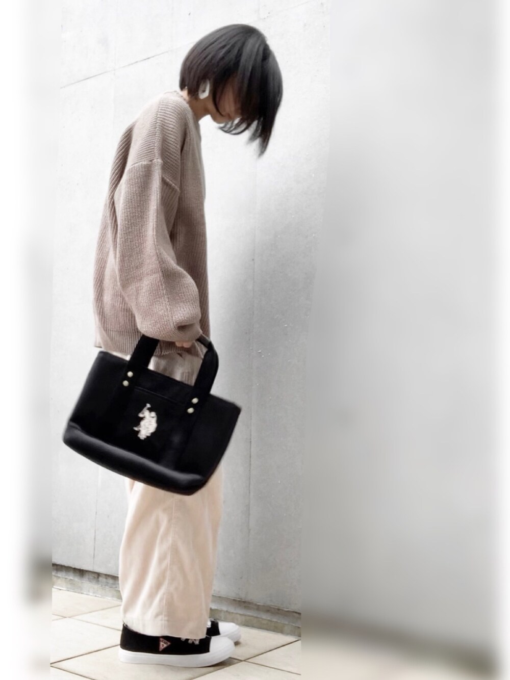 ブラウン系のニット/セーター、ブラック系のトートバッグ、ブラック系のスニーカーを着用したレディースの秋コーディネートの1枚目の写真