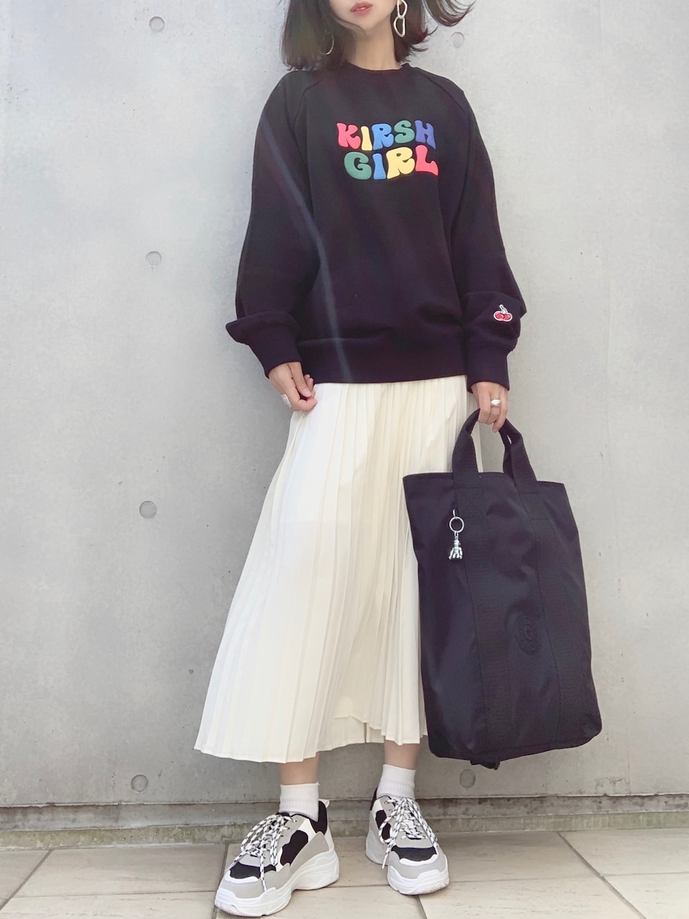 ブラック系のスウェット、ホワイト系のスカート、ブラック系のスニーカーを着用したレディースの春コーディネートの1枚目の写真