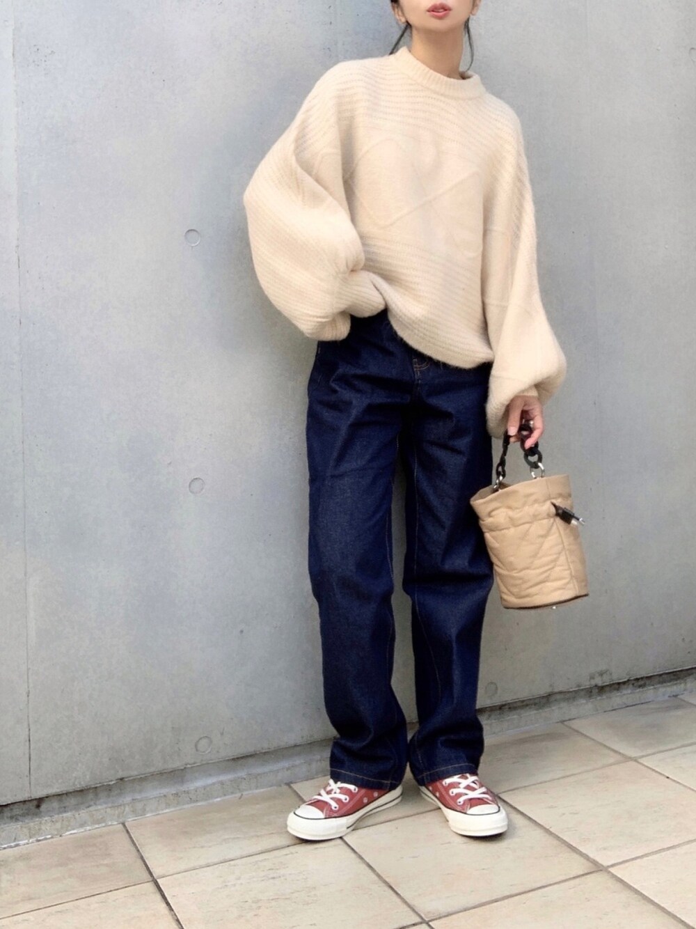 ブルー系のデニムパンツ、ホワイト系のニット/セーター、オレンジ系のスニーカーを着用したレディースの冬コーディネートの1枚目の写真