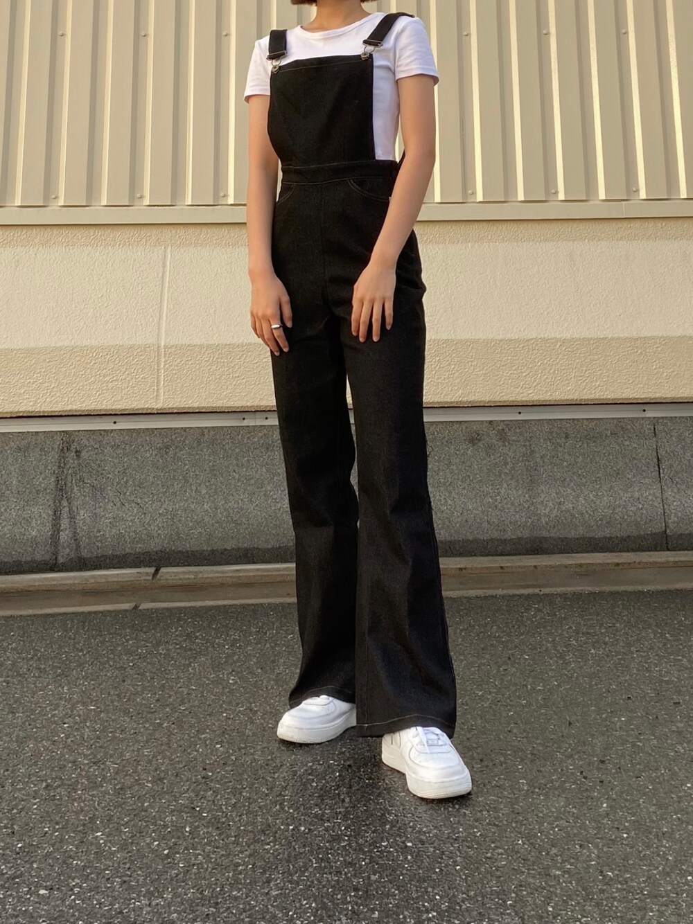 ホワイト系のトップス、ブラック系のサロペット/オーバーオール、ホワイト系のスニーカーを着用したレディースの春コーディネートの1枚目の写真