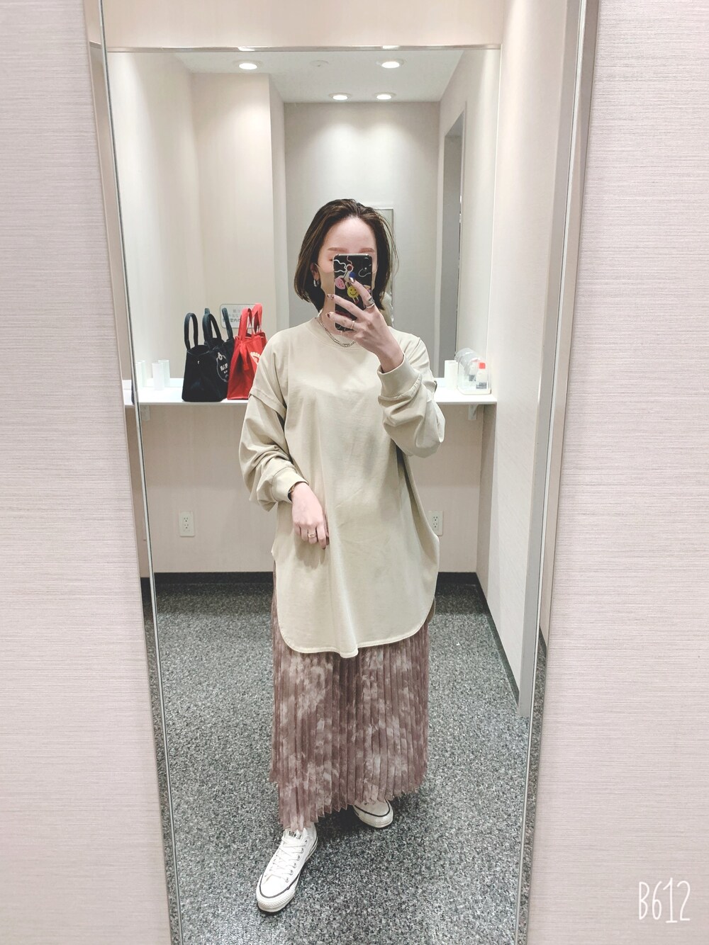 ベージュ系のTシャツ/カットソー、ベージュ系のスカート、ホワイト系のスニーカーを着用したレディースの冬コーディネートの1枚目の写真