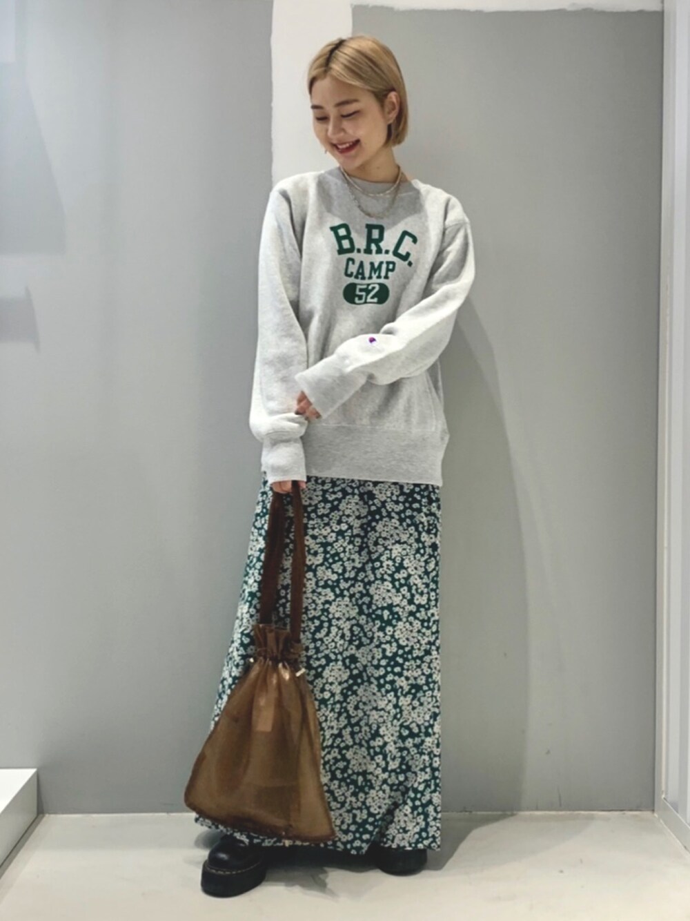 グリーン系のスカートを着用したレディースの秋コーディネートの1枚目の写真