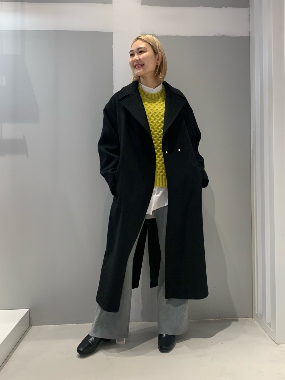 ブラック系のその他アウター、グレー系のその他パンツ、イエロー系のニット/セーターを着用したレディースの冬コーディネートの1枚目の写真