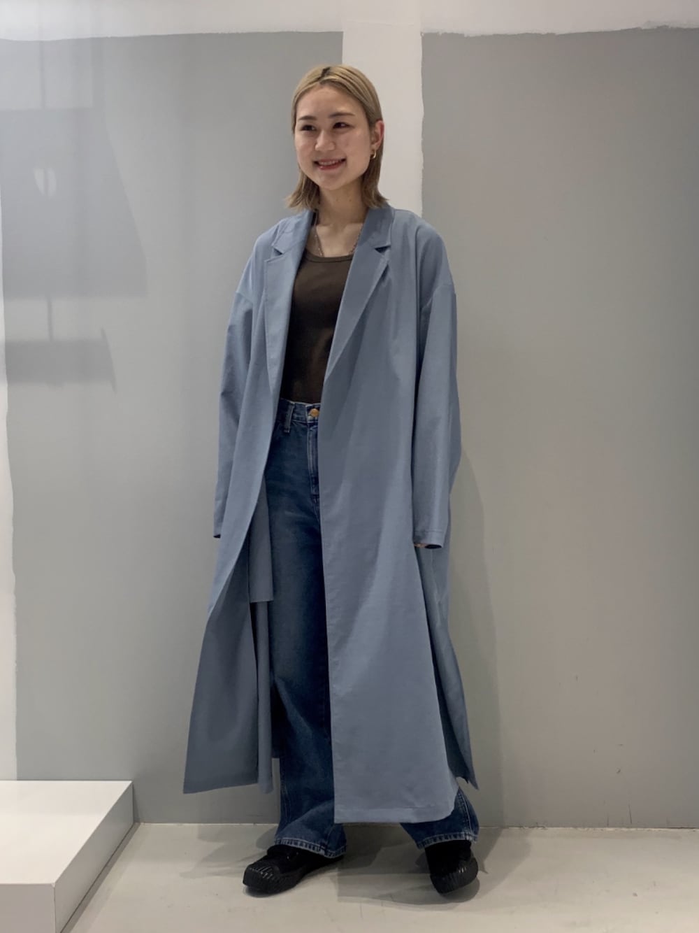 ブルー系のトレンチコート、ブラック系のスニーカーを着用したレディースの冬コーディネートの1枚目の写真