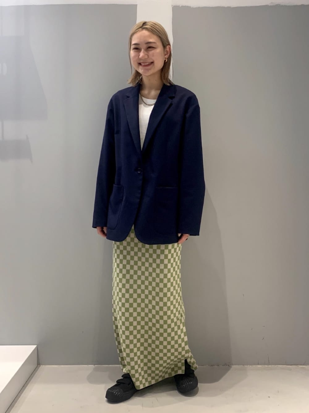 ブルー系のテーラードジャケット、グリーン系のスカート、ブラック系のスニーカーを着用したレディースの冬コーディネートの1枚目の写真