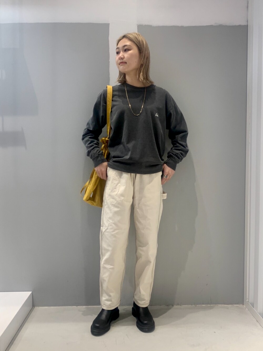 グレー系のトップス、ホワイト系のパンツ、ブラック系のパンプスを着用したレディースの冬コーディネートの1枚目の写真