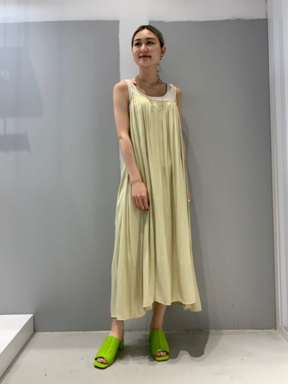 イエロー系のワンピース、グリーン系のサンダルを着用したレディースの春コーディネートの1枚目の写真