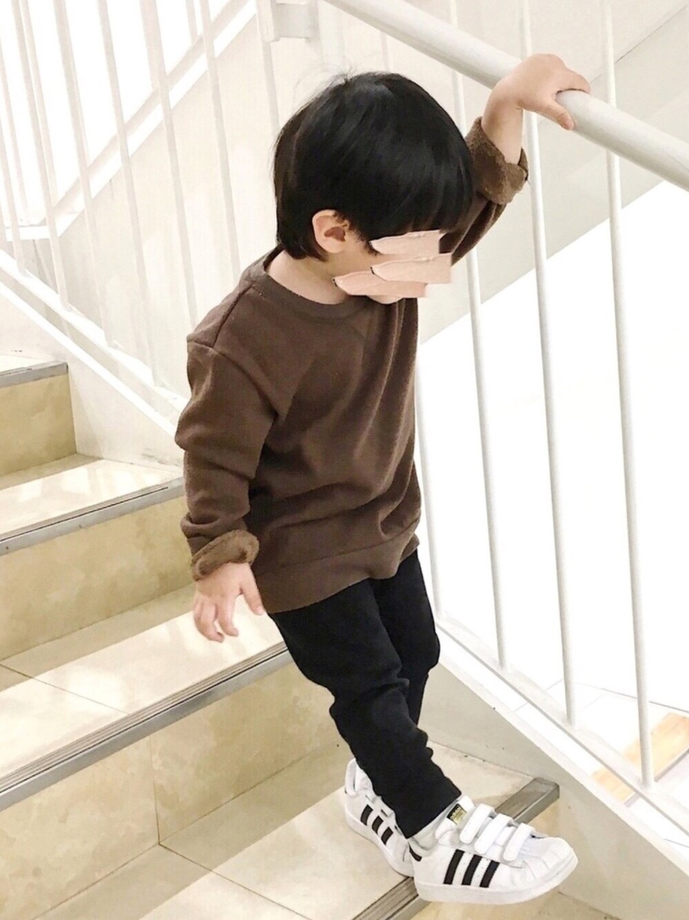 ブラウン系のスウェット、ブラック系のパンツ、ホワイト系のスニーカーを着用したキッズの冬コーディネートの1枚目の写真