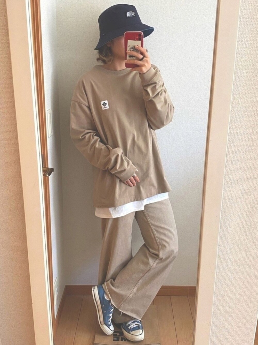 ベージュ系のTシャツ/カットソー、ベージュ系のパンツ、ブルー系のスニーカーを着用したレディースの秋コーディネートの1枚目の写真