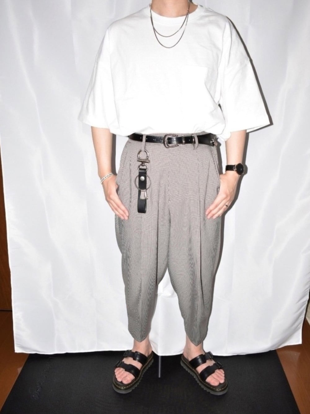 ホワイト系のTシャツ/カットソー、ベージュ系のスラックス、ブラック系のサンダルを着用したメンズの春コーディネートの1枚目の写真