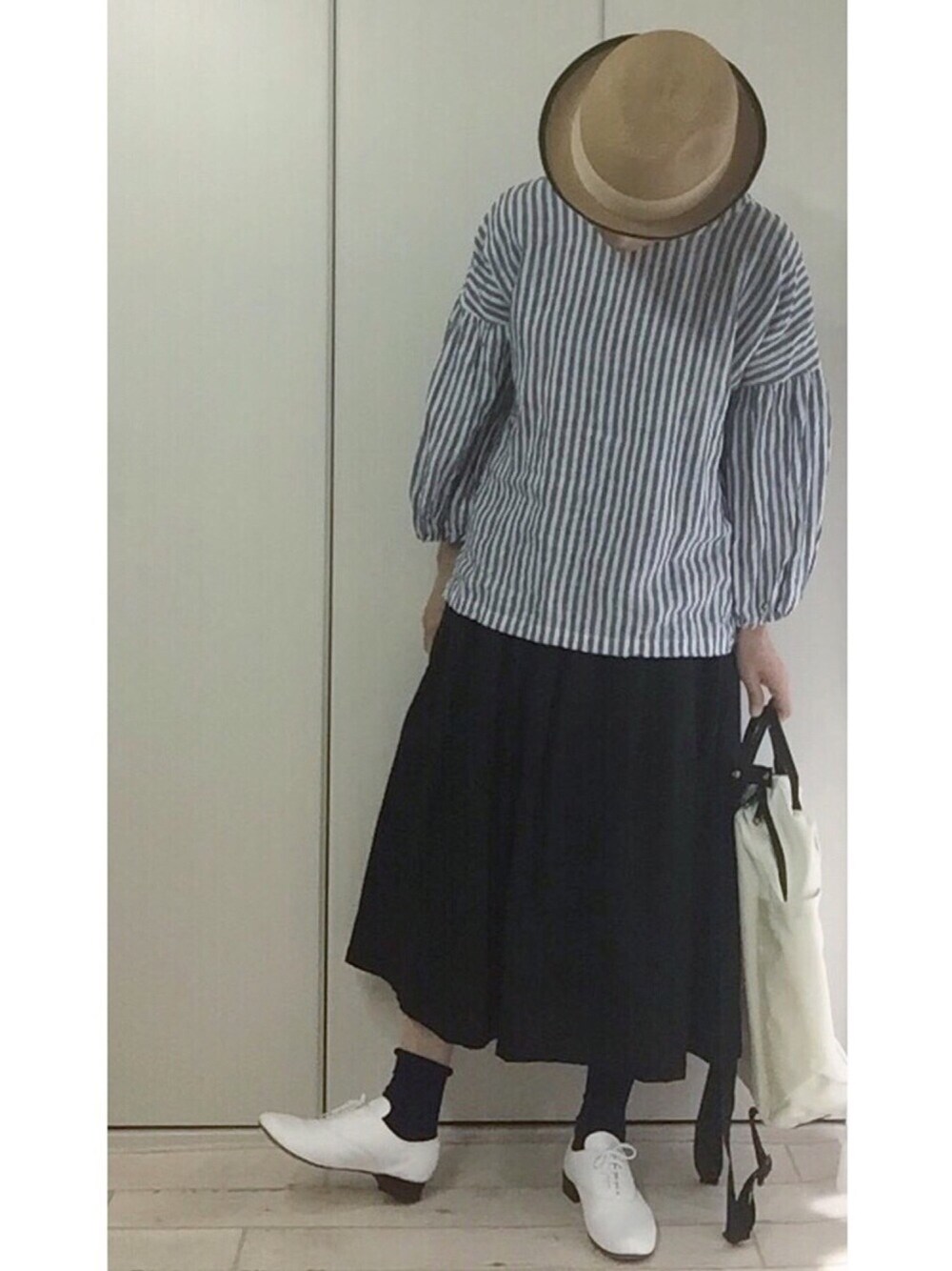 ブラック系のスカート、ブルー系のシャツ/ブラウス、ホワイト系のバックパック/リュックを着用したレディースの冬コーディネートの1枚目の写真