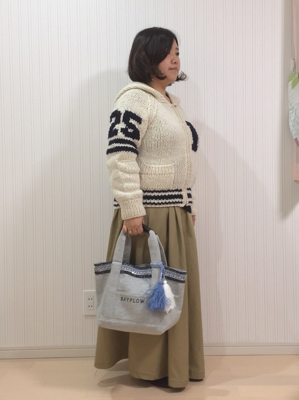 ホワイト系のカーディガン/ボレロ、グレー系のトートバッグ、ベージュ系のスカートを着用したレディースの冬コーディネートの1枚目の写真