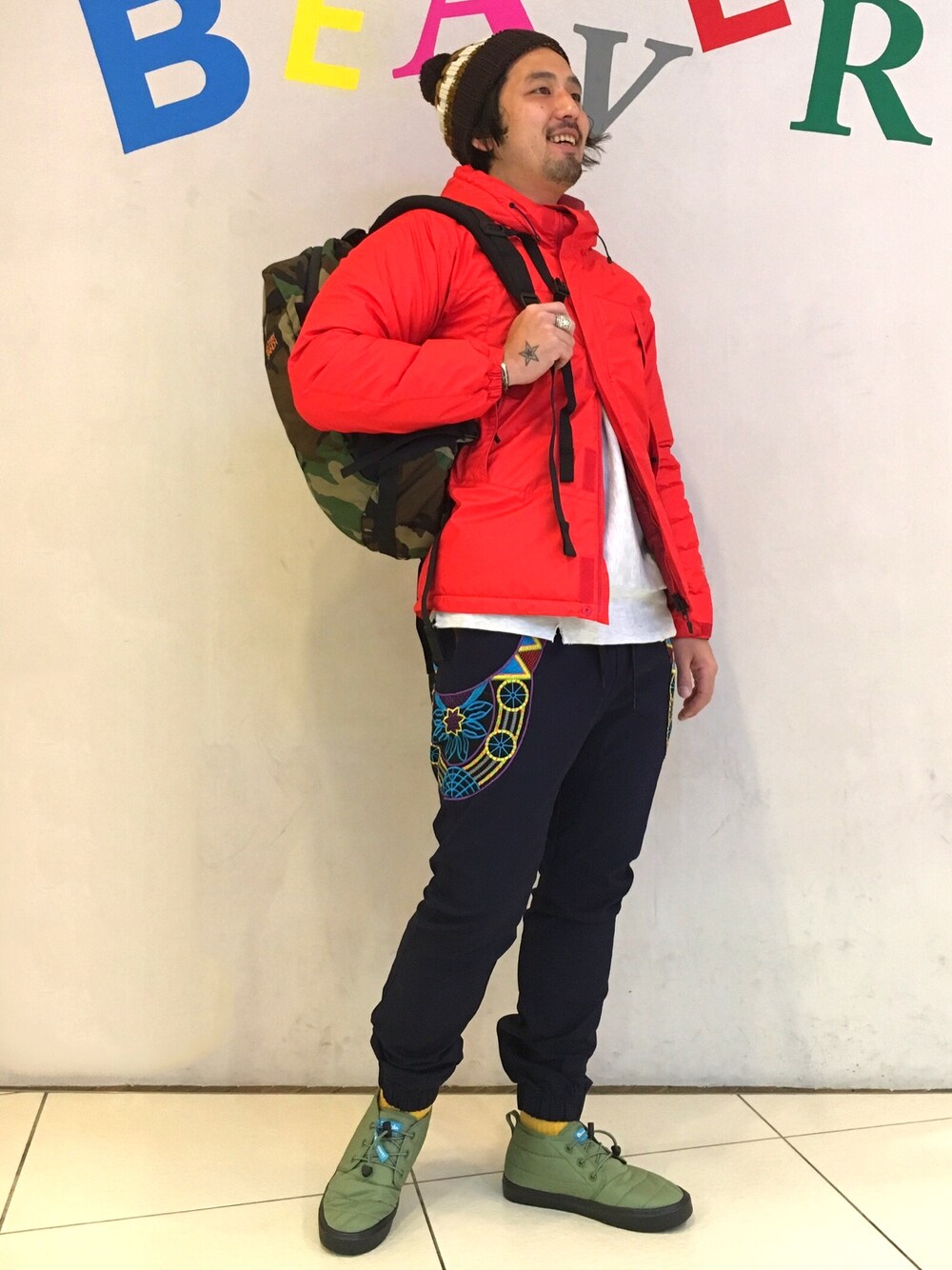 レッド系のマウンテンパーカー、ブルー系のその他パンツ、グリーン系のスニーカーを着用したメンズの冬コーディネートの1枚目の写真