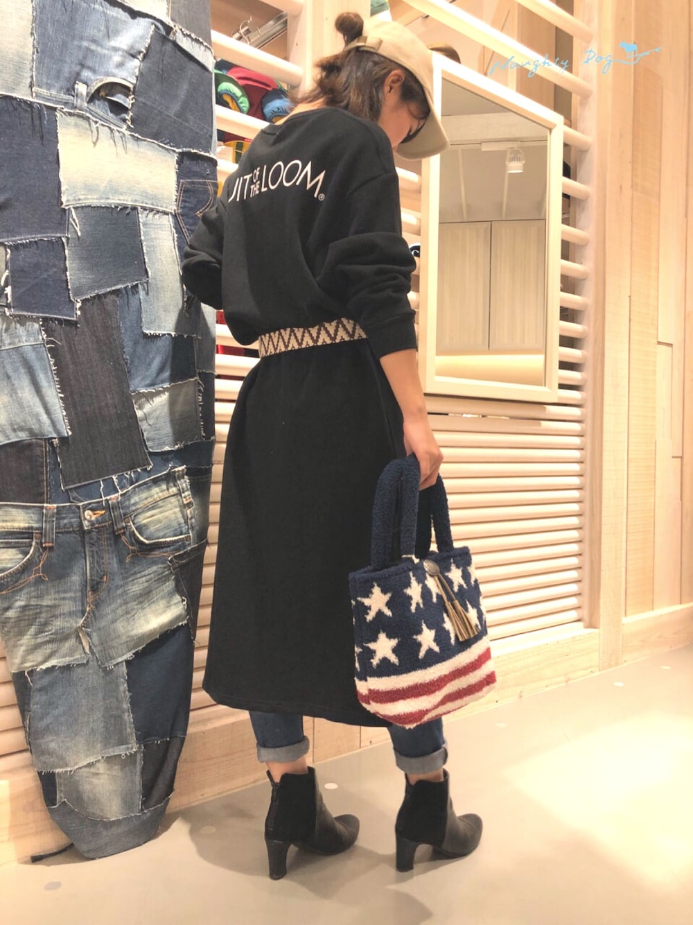 ブラック系のチュニック、ブルー系のデニムパンツ、ホワイト系のトートバッグを着用したレディースの冬コーディネートの1枚目の写真