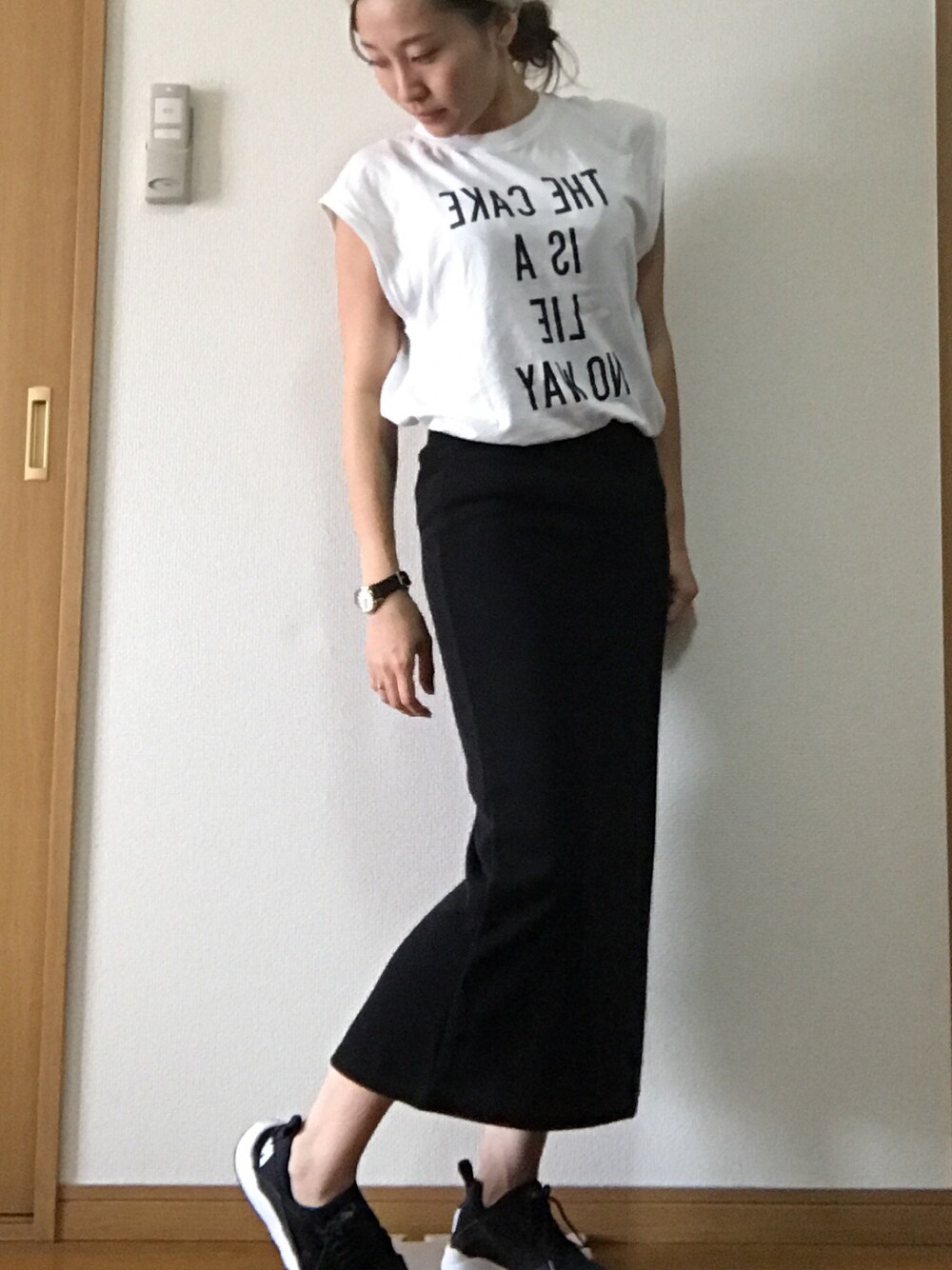 ブラック系のスカート、ホワイト系のTシャツ/カットソー、ブラック系のスニーカーを着用したレディースの夏コーディネートの1枚目の写真