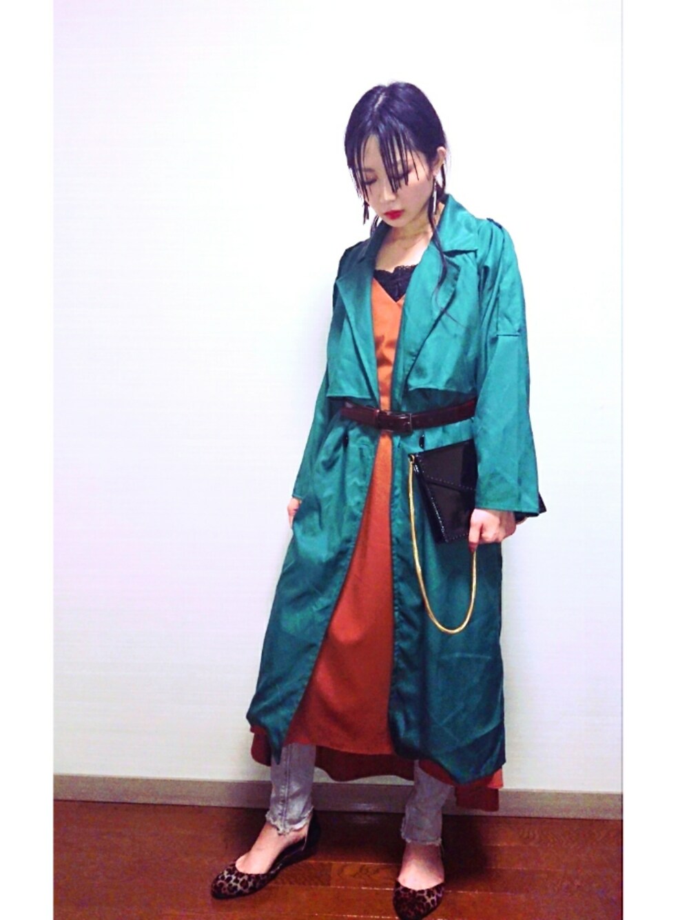 グリーン系のトレンチコート、ブラウン系のシューズ、オレンジ系のワンピースを着用したレディースの秋コーディネートの1枚目の写真