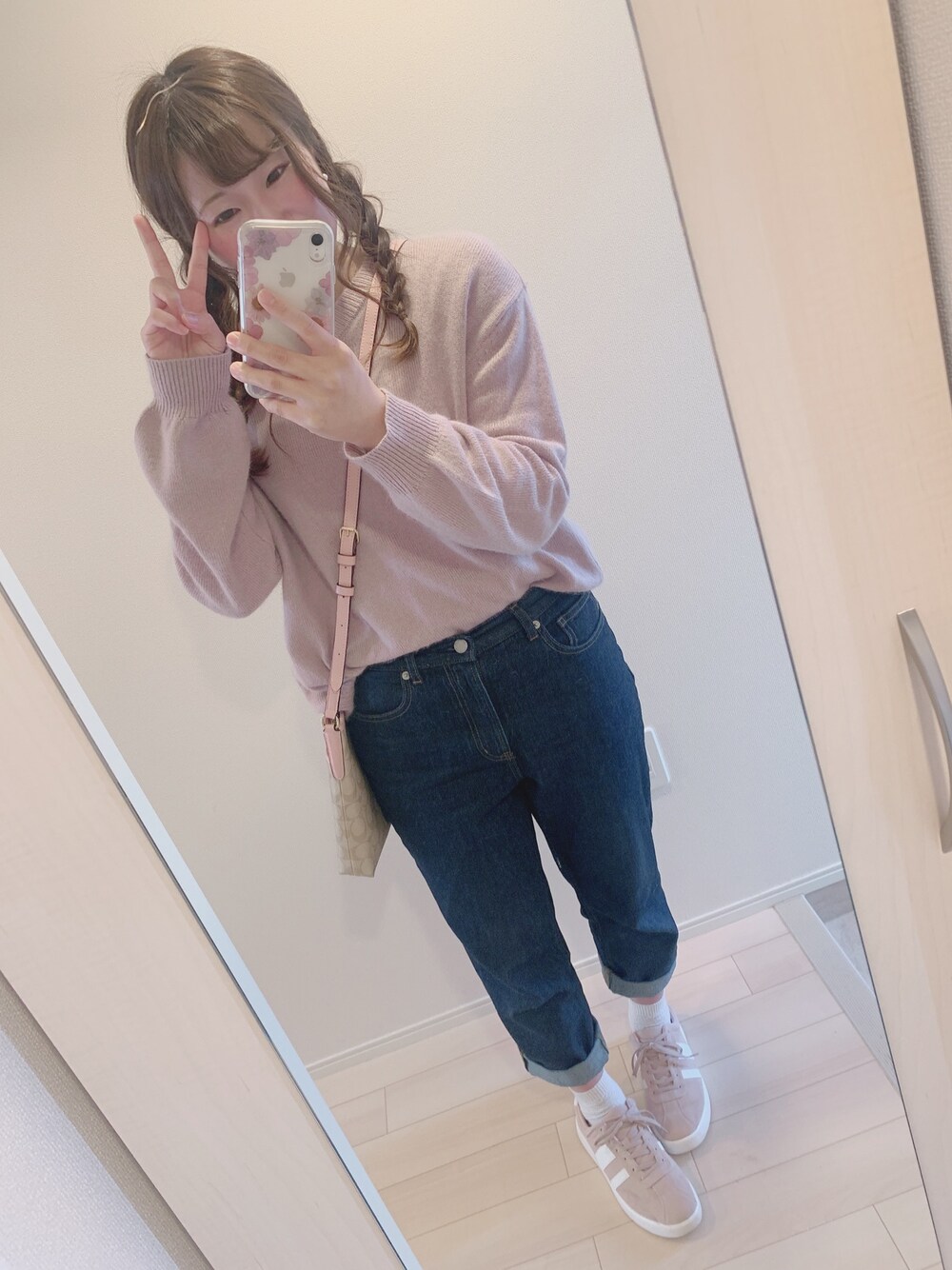 ピンク系のニット/セーター、ブルー系のデニムパンツ、ベージュ系のバッグを着用したレディースの春コーディネートの1枚目の写真