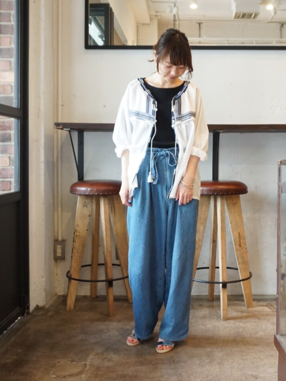 ブルー系のデニムパンツ、ホワイト系のシャツ/ブラウス、ブラック系のTシャツ/カットソーを着用したレディースの春コーディネートの1枚目の写真