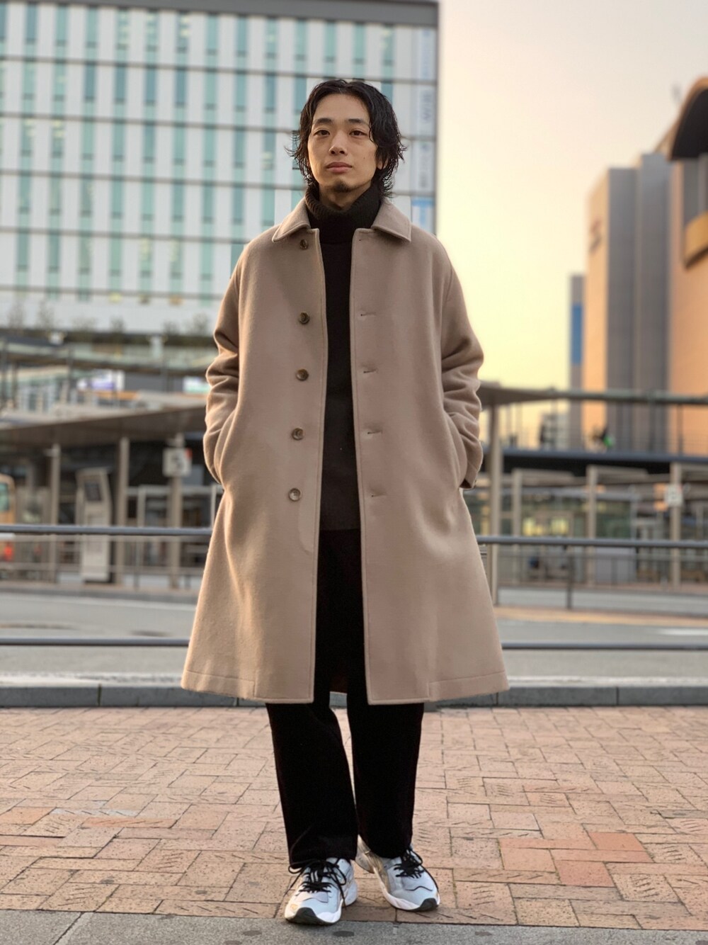 ベージュ系のステンカラーコート、ブラウン系のニット/セーター、ブラック系のその他パンツを着用したメンズの冬コーディネートの1枚目の写真