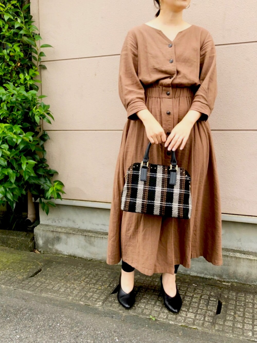 ブラック系のハンドバッグ、ブラック系のパンプス、ブラウン系のワンピースを着用したレディースの秋コーディネートの1枚目の写真