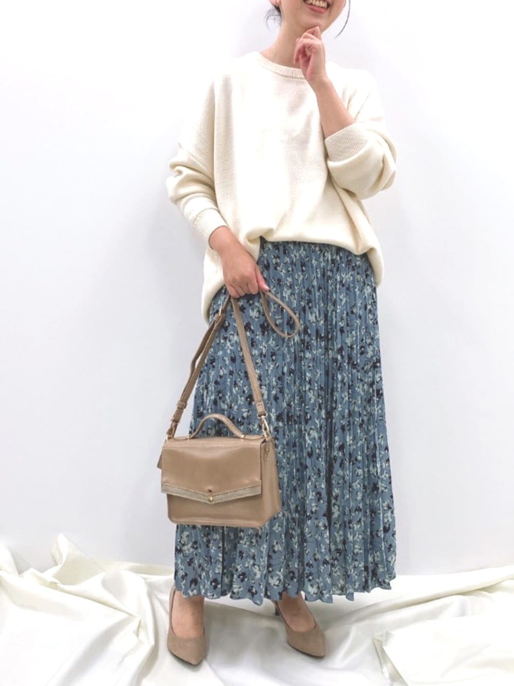 ブラウン系のショルダーバッグ、ホワイト系のニット/セーター、ブルー系のスカートを着用したレディースの冬コーディネートの1枚目の写真