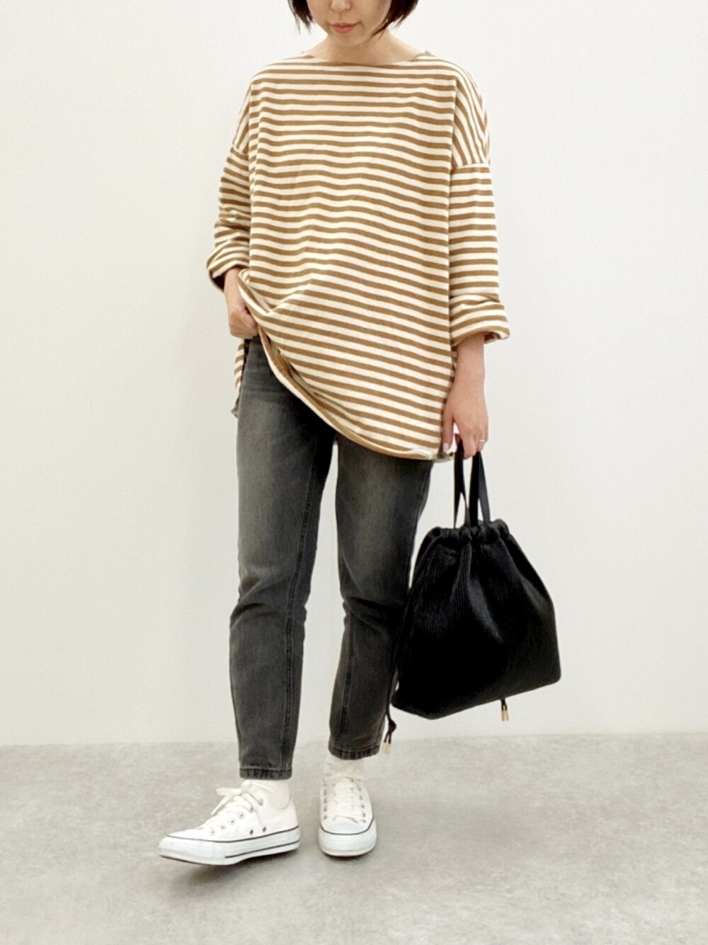 ベージュ系のTシャツ/カットソー、ブラック系のトートバッグ、ホワイト系のスニーカーを着用したレディースの春コーディネートの1枚目の写真
