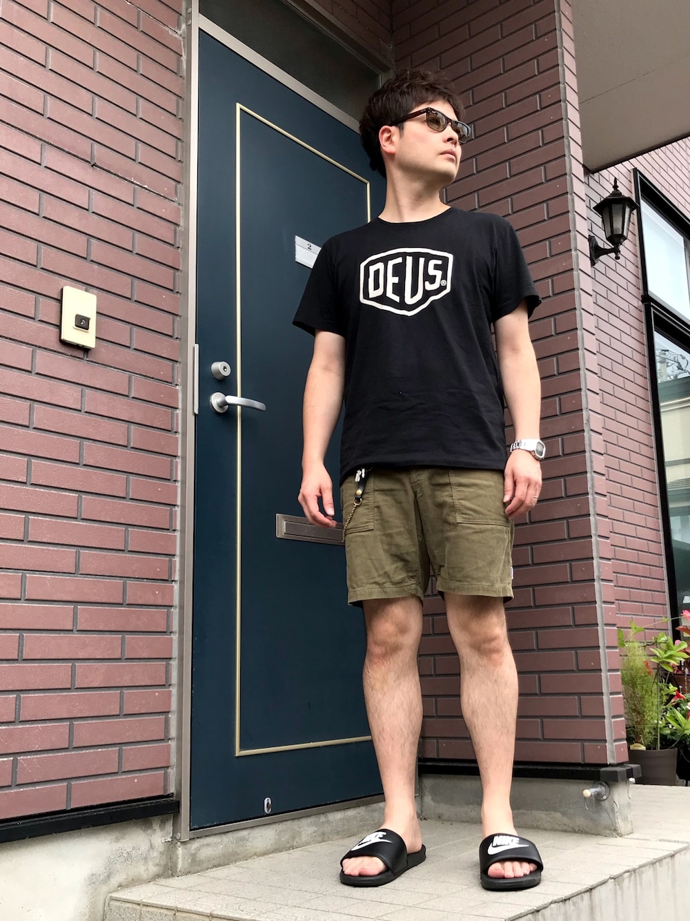 ブラック系のTシャツ/カットソー、グリーン系のパンツ、ブラック系のサンダルを着用したメンズの夏コーディネートの1枚目の写真