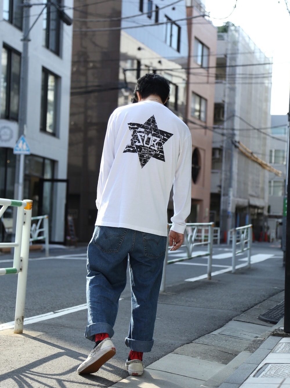 ホワイト系のTシャツ/カットソー、ブルー系のデニムパンツ、ベージュ系のスリッポンを着用したメンズの秋コーディネートの1枚目の写真