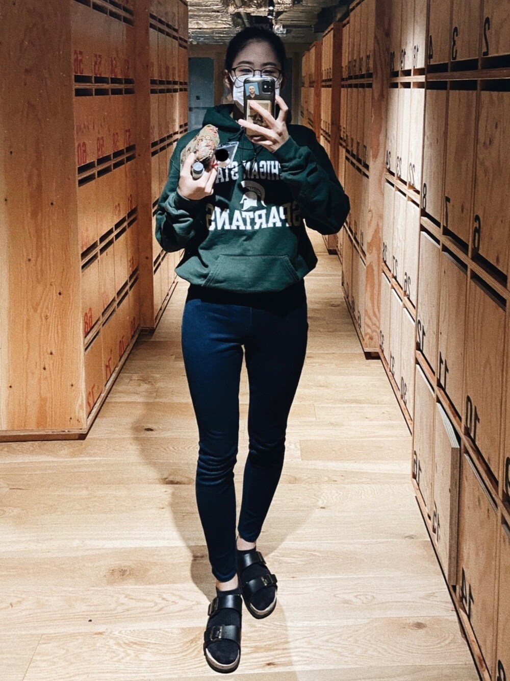 ブルー系のデニムパンツ、グリーン系のパーカー、ブラック系のメガネを着用したレディースの秋コーディネートの1枚目の写真