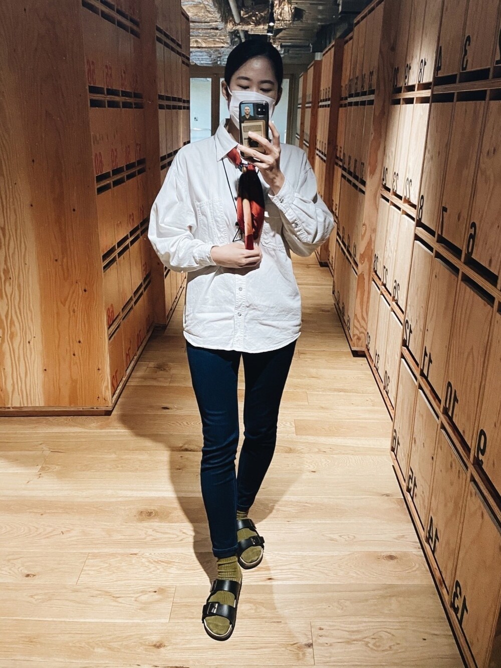 ブルー系のデニムパンツ、ホワイト系のシャツ/ブラウス、レッド系のマフラーを着用したレディースの秋コーディネートの1枚目の写真