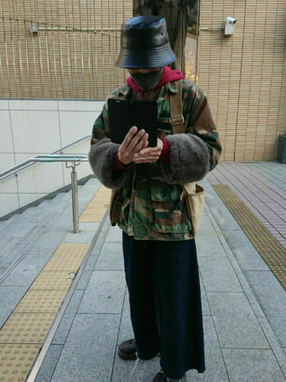 グリーン系のミリタリージャケット、ブラウン系のベスト、ブルー系のデニムパンツを着用したメンズの冬コーディネートの1枚目の写真