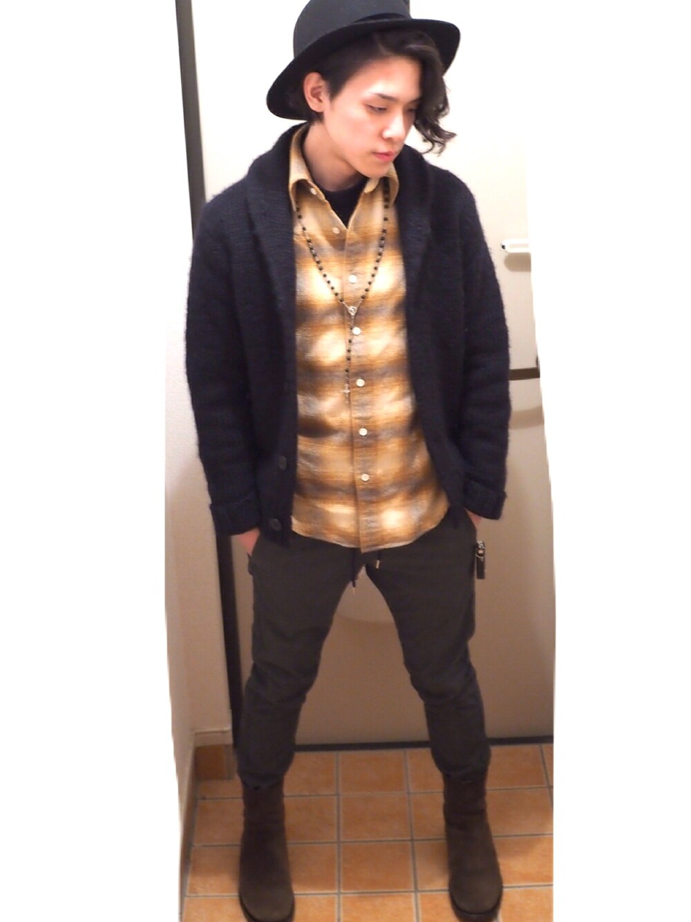 ブラック系のニット/セーター、ブラウン系のブーツ、イエロー系のシャツ/ブラウスを着用したメンズの冬コーディネートの1枚目の写真