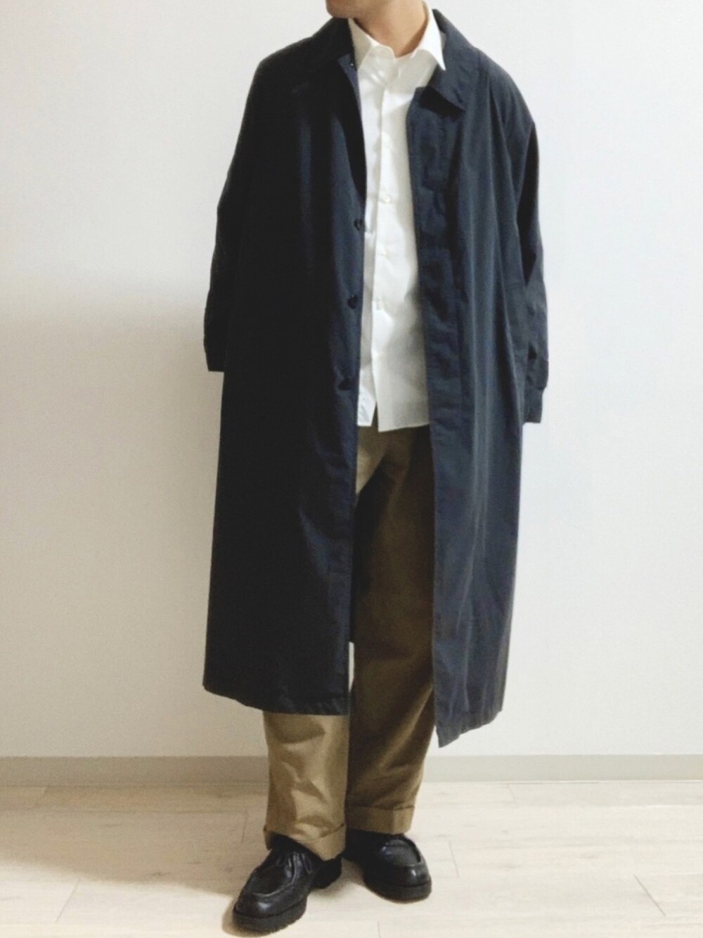 ブラック系のステンカラーコート、ホワイト系のシャツ/ブラウス、ベージュ系のその他パンツを着用したメンズの春コーディネートの1枚目の写真