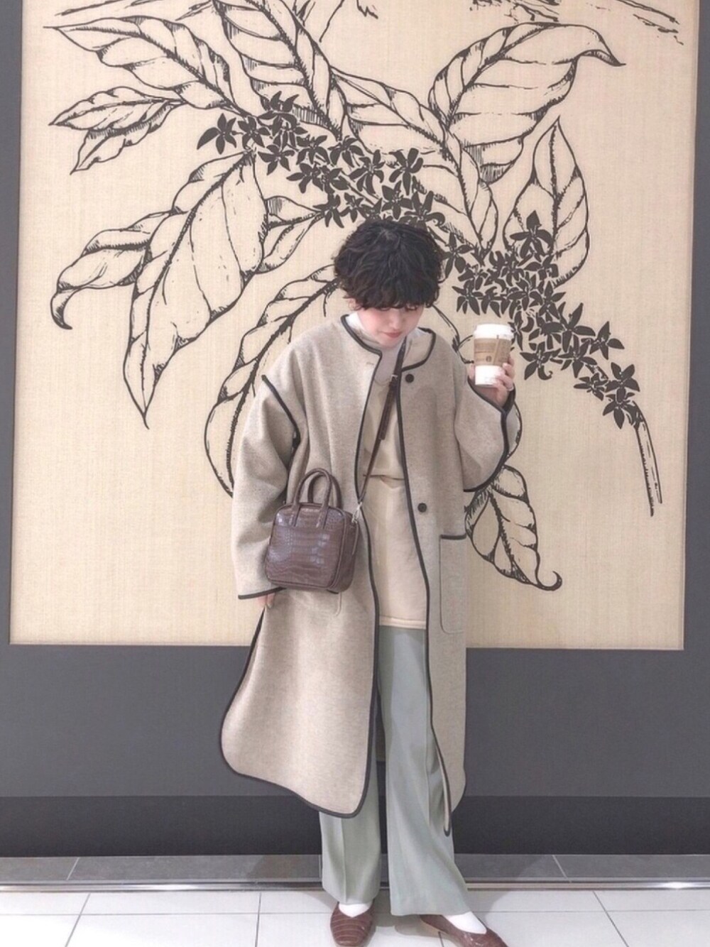 ホワイト系のノーカラーコート、ホワイト系のスウェット、ブラウン系のショルダーバッグを着用したレディースの冬コーディネートの1枚目の写真