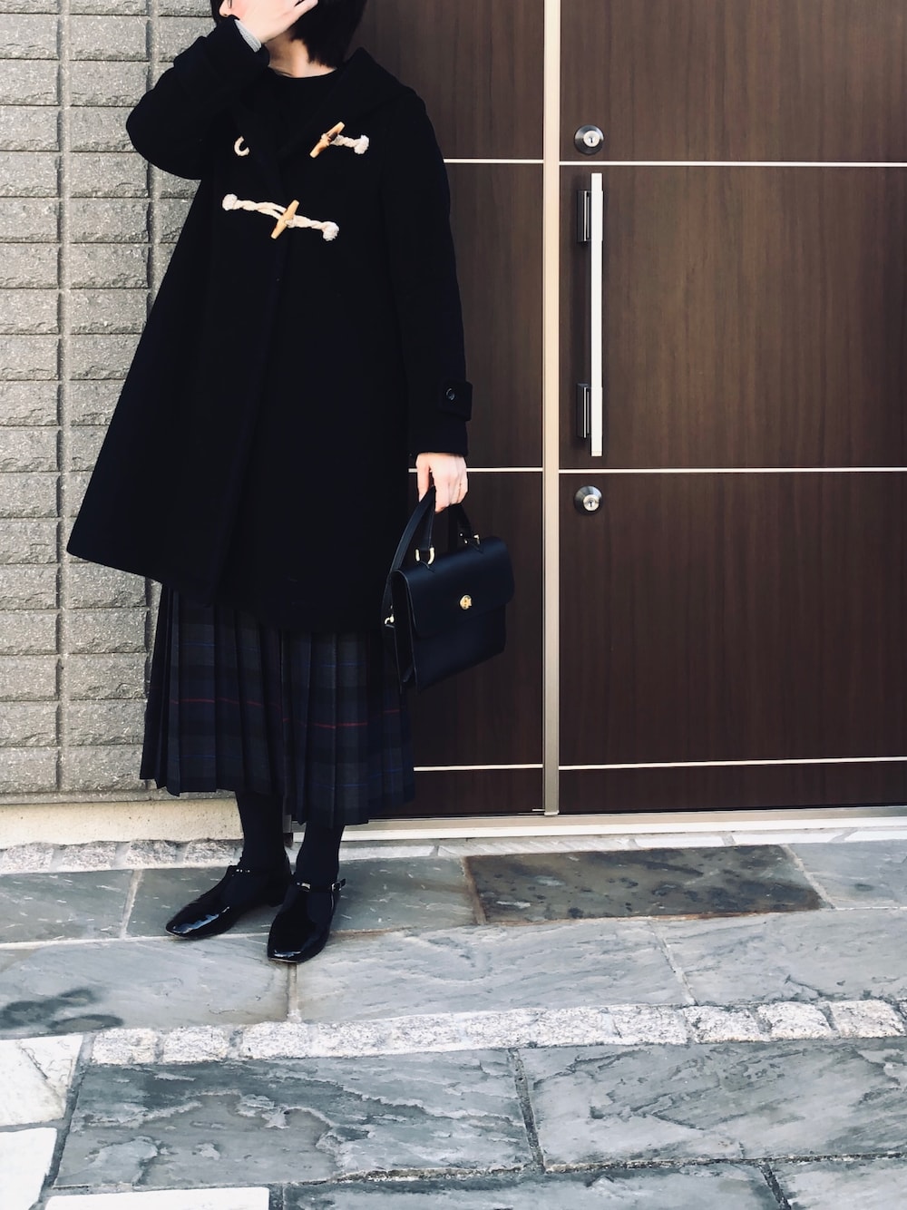 ブラック系のダッフルコート、ブルー系のニット/セーター、グレー系のスカートを着用したレディースの冬コーディネートの1枚目の写真