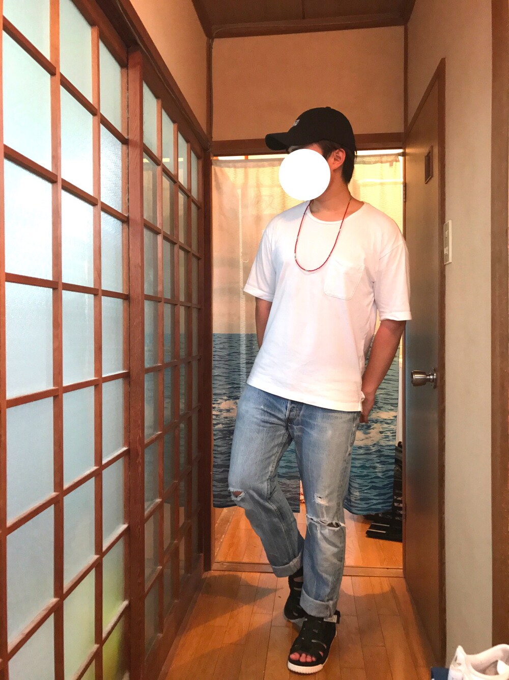 ホワイト系のTシャツ/カットソー、ブルー系のデニムパンツ、ブラック系のサンダルを着用したメンズの夏コーディネートの1枚目の写真