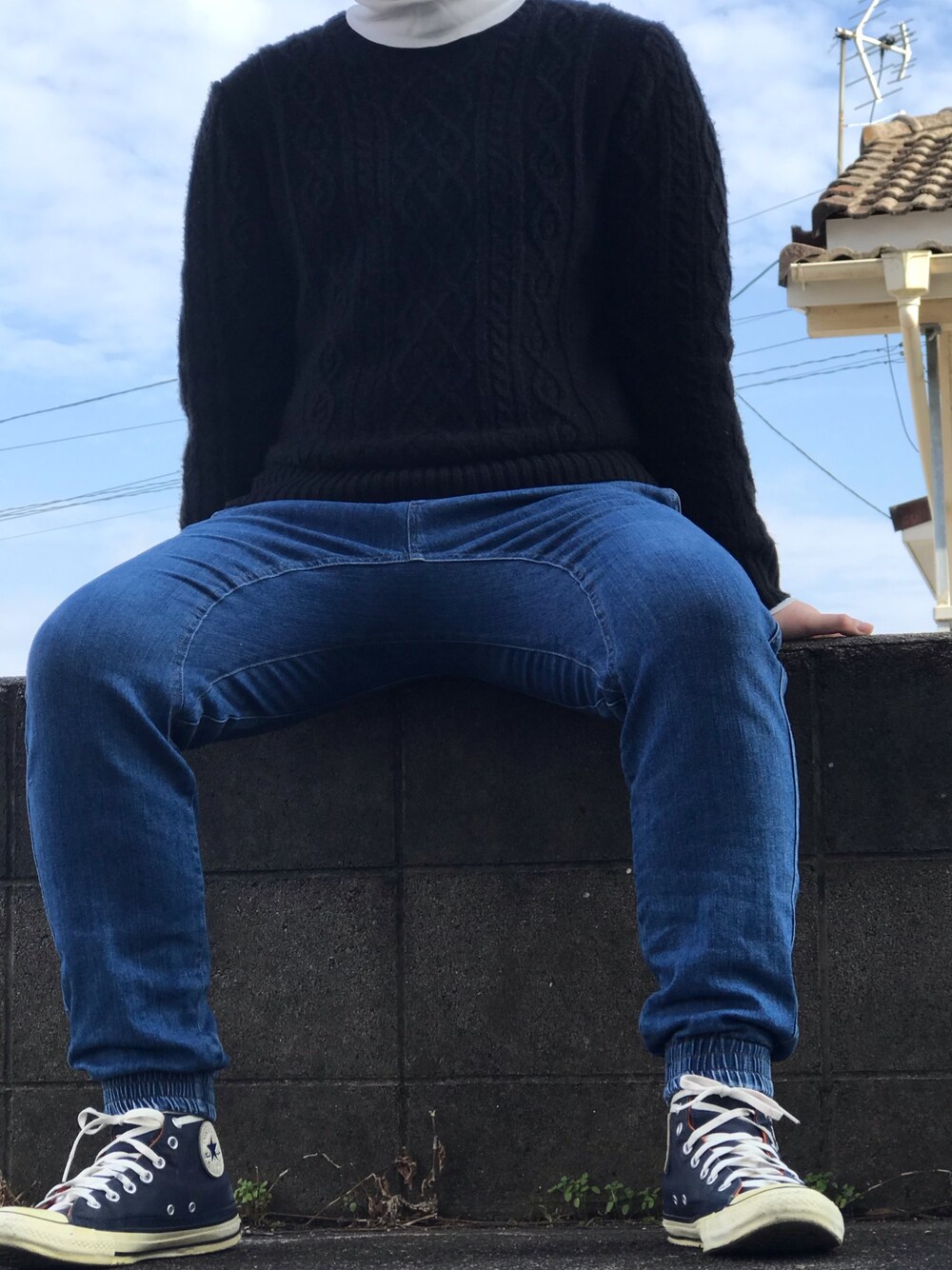 ブラック系のニット/セーター、ホワイト系のTシャツ/カットソー、ブルー系のデニムパンツを着用したメンズの冬コーディネートの1枚目の写真