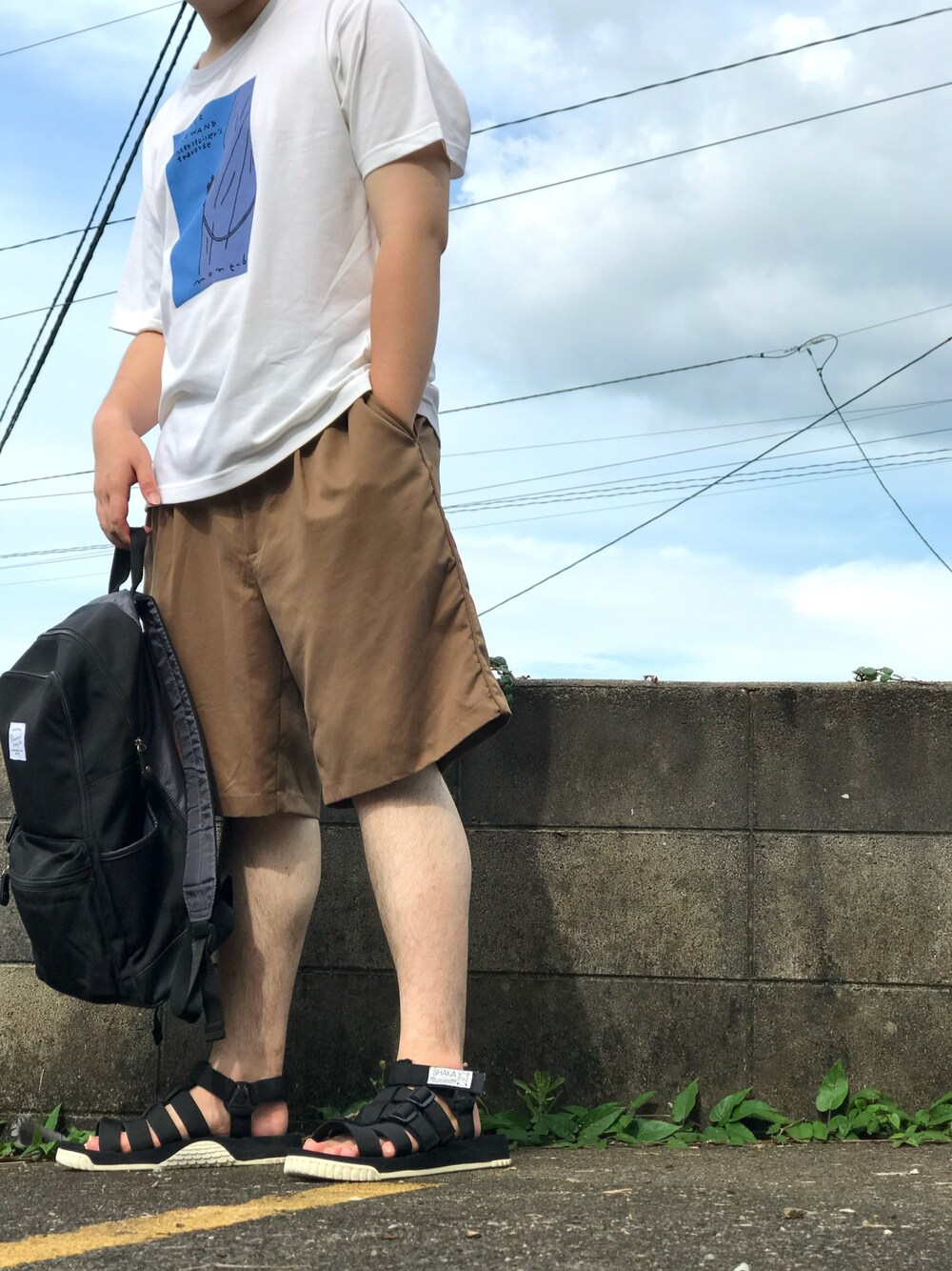 ホワイト系のTシャツ/カットソー、ブラック系のサンダル、ブラック系のバックパック/リュックを着用したメンズの夏コーディネートの1枚目の写真