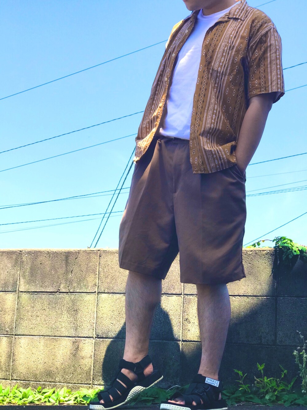 イエロー系のシャツ/ブラウス、ブラウン系のチノパンツ、ブラック系のサンダルを着用したメンズの夏コーディネートの1枚目の写真