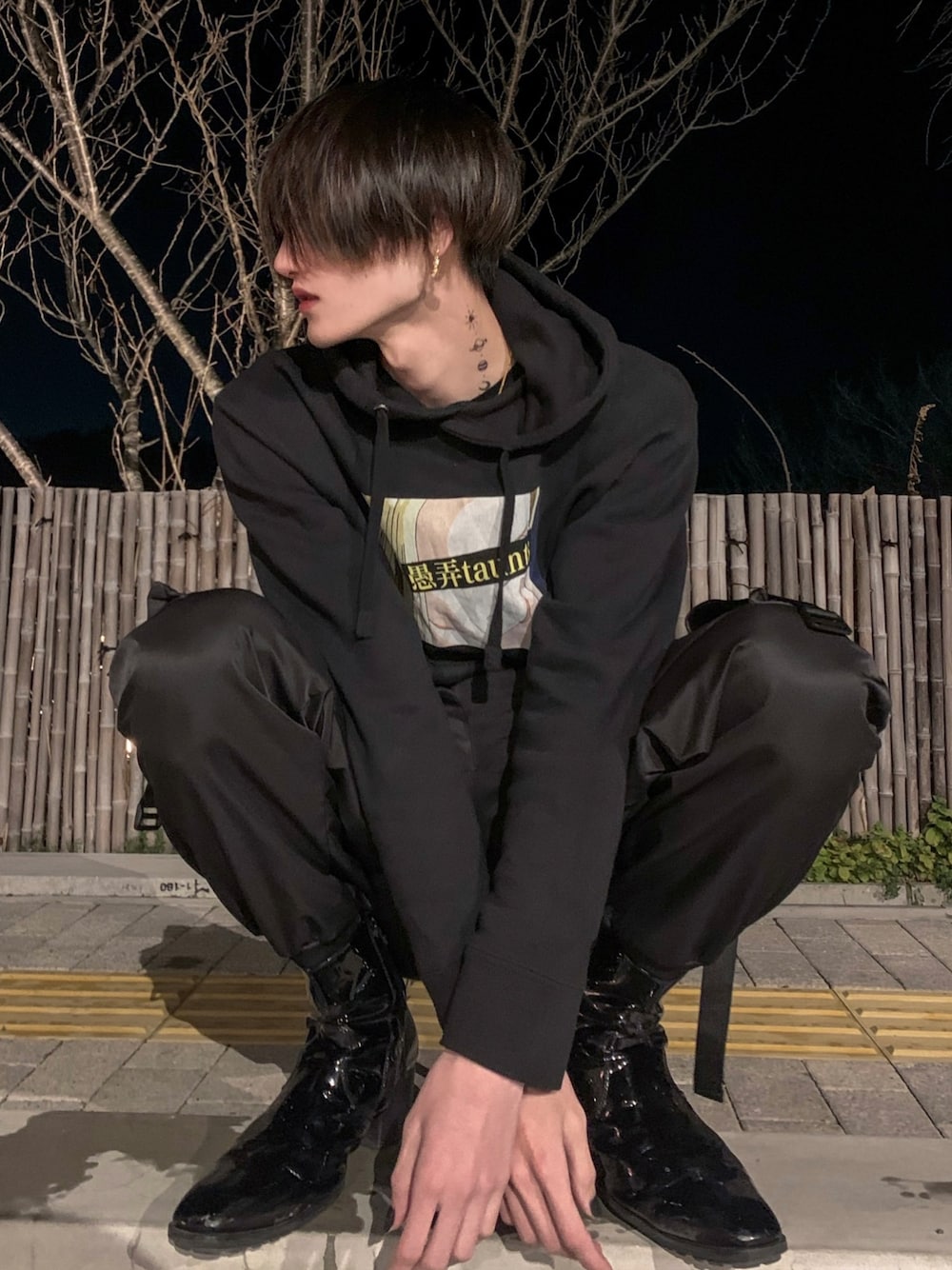 ブラック系のパーカー、ブラック系のカーゴパンツ、ブラック系のブーツを着用したメンズの春コーディネートの1枚目の写真