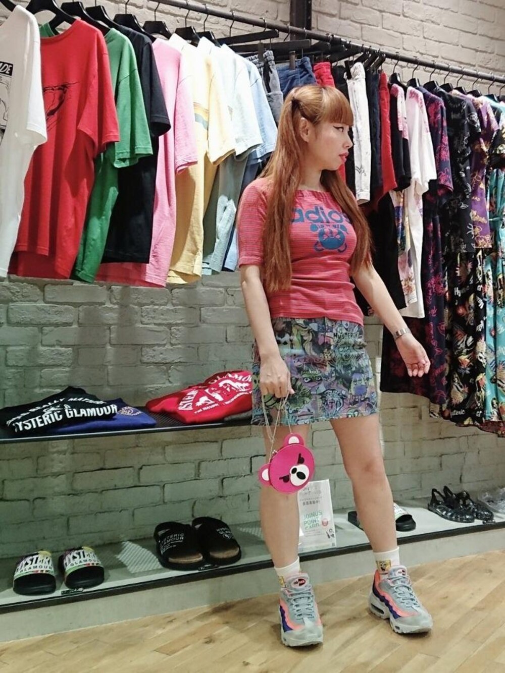 ブルー系のデニムスカート、ピンク系のTシャツ/カットソー、ピンク系のポーチを着用したレディースの夏コーディネートの1枚目の写真