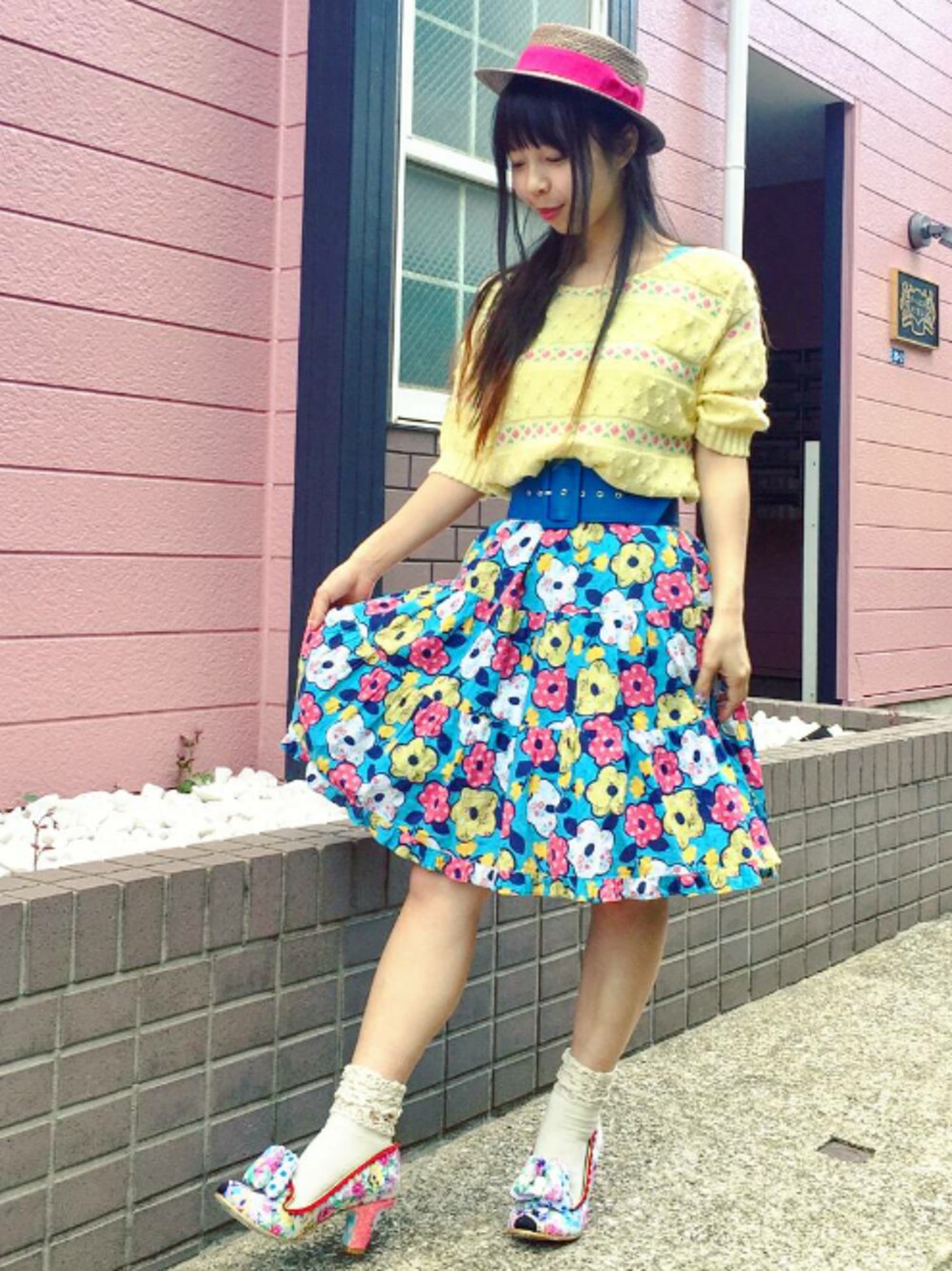 ホワイト系のパンプス、ブルー系のスカート、イエロー系のニット/セーターを着用したレディースの夏コーディネートの1枚目の写真