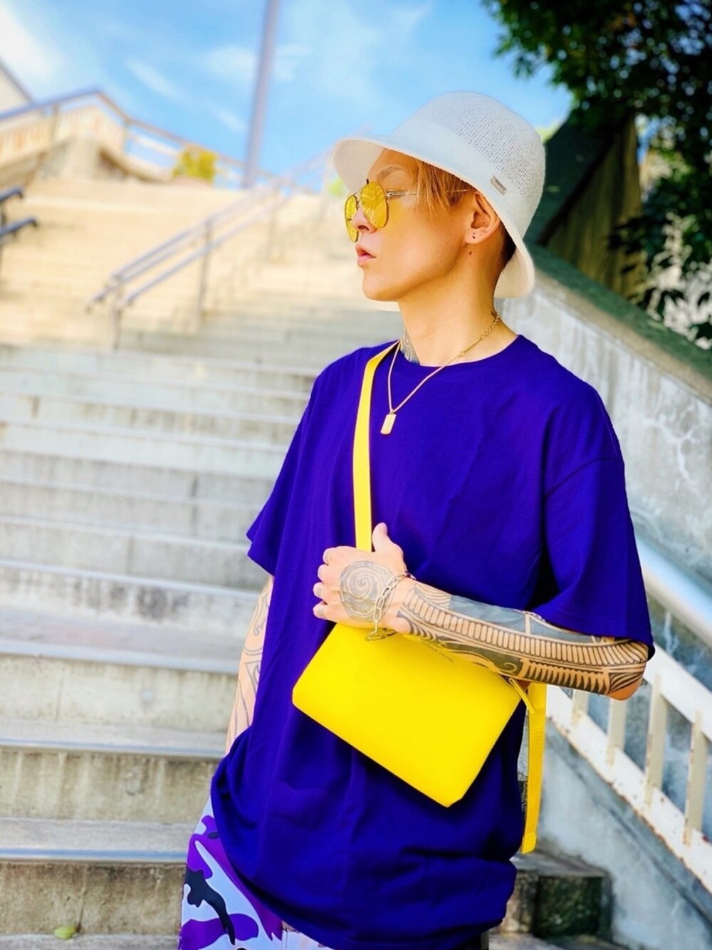 「サコッシュ、NUMBER (N)INE、ゴールドアクセ、POLICE、ブレスレット、パープル、バケットハット、カモフラパンツ、CASPER JOHN AIVER、AIVER」｜「NUMBER (N)INEの【NUMBER (N)INE】≪WEB限定≫別注スーベニアプレミアムPUレザーサコッシュ（ショルダーバッグ、イエロー系）」を使った、TETUさん（メンズ・174cm）の夏コーディネートの1枚目の写真