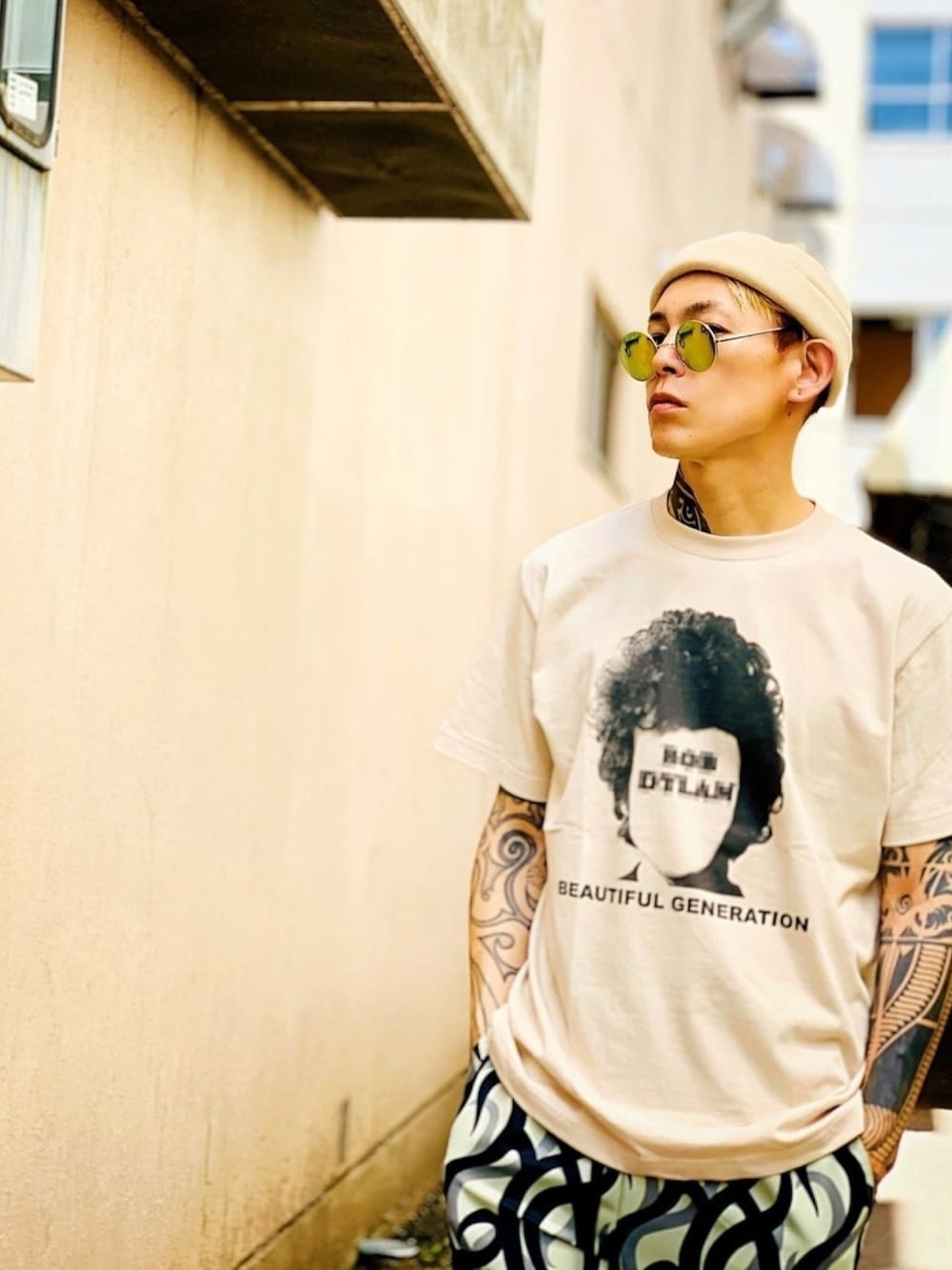 「ベージュ、Tシャツ、グラフィックＴ、シンプルコーデ、ロールキャップ、NUMBER (N)INE、柄パンツ、丸サングラス、夏、Tシャツコーデ」｜「NUMBER (N)INEの【NUMBER (N)INE】《別注》ヒューマンフェイス モザイクロゴ プリント クルーネック Tシャツ（Tシャツ/カットソー、ベージュ系）」を使った、TETUさん（メンズ・174cm）の夏コーディネートの1枚目の写真